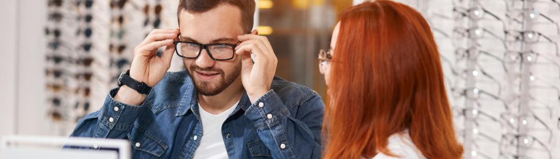Woman helping a man try out new eye glasses